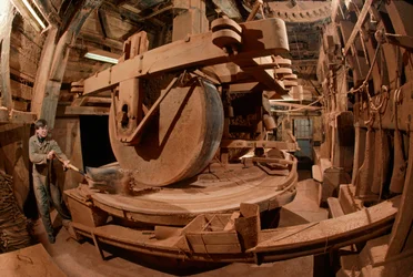 Een man maalt cacaoboonenschillen voor diervoeder in een 100 jaar oude molen. Ooievaar Molen