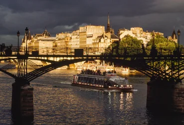 Donkere wolken boven een boot die onder de Pont des Arts vaart. Seine, Parijs