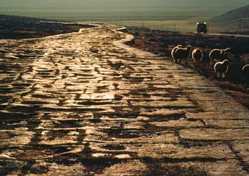 Moderne macadamweg parallel aan oude kalkstenen Romeinse weg. Nabij Aleppo, Syrië