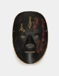 Achterkant van een houten masker bedekt met sumi, gelakt met inscripties in rood