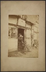 [Zittende man drinkt uit mok in open deuropening].
