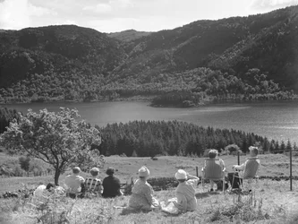 Groep mensen zittend op gras of ligstoelen kijkend naar uitzicht op Thirlmere