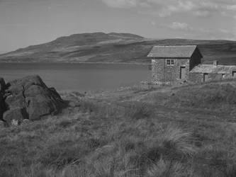 Rotsen op de voorgrond links en gebouw rechts met daarachter Devoke Water