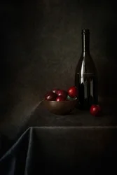 Stilleven met pruimen en een fles