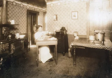 Vrouw die borstelharen in tandenborstels steekt in haar keuken, c.1912