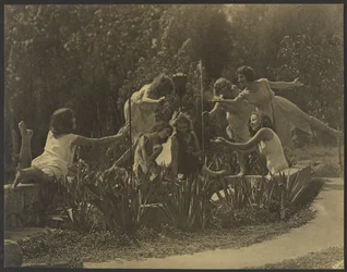 [Dansers poseren langs de tuinmuur]