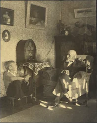 [Man en jongen zitten in een studeerkamer].