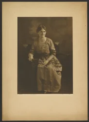 [Portret van een zittende vrouw in jurk met lintaccenten].