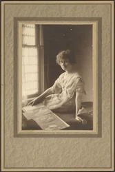 [Portret van een vrouw die naar een album kijkt].