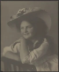 [Portret van een jonge vrouw die op een stoel leunt]