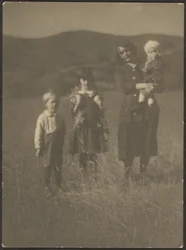 [Vrouw en drie kinderen in het veld]