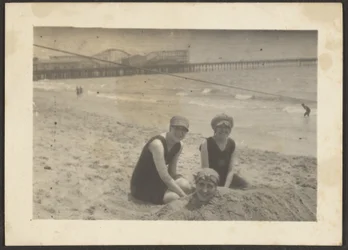 [Vrouwen op het strand die een vriendin in het zand begraven]
