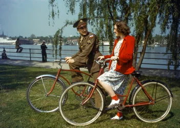 Zittend op fietsen bij een haven, US Army officier flirt met een jonge vrouw op Trinidad