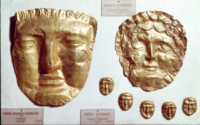 Fenicische kunst: grote gouden maskers op het gezicht van vrouw en man en groep van vijf kleine gouden maskers onderaan