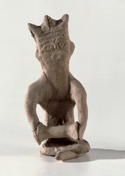 Gekruiste figuur met een object dat vermoedelijk een trommel is, uit Susa, Iran, 4e-6e eeuw AD (been)