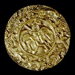 Archeologie van de Middeleeuwen. Barbaarse kunst van Lombardije: gouden schijf. In het midden een heilige te paard met een speer en rondom diermotieven. Lombardische kunst, rond 600. Italië, Cividale del Friuli, Archeologisch Museum