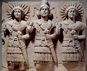 Palmyreense triade: Baalshamin, heer van de hemel tussen de maangod en de zonnegod. Laag reliëf in kalksteen uit de 1e eeuw. Uit Palmyra, Syrië. Afmetingen: 0,6 x 0,72 m. Parijs, Musée du Louvre