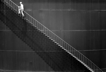 Man klimt trappen op de zijkant van een olietank