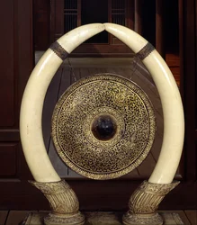 Een gong hangend aan olifantenslagtanden (metaal en ivoor)