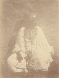 [Portret van een Noord-Afrikaanse vrouw zittend tegen een muur].