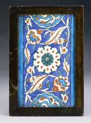 Een Iznik Randtegel, met een Centrale Bloemkop tussen Krullende Palmet en Bladerrank