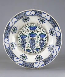 Een Iznik aardewerkschotel, met een centraal rondel met drie trossen druiven en wijnbladeren, ca.1570