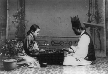 Een man en een vrouw die een spel baduk of "go" spelen, ca. 1910