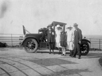 Een groep mensen voor hun auto aan zee, ca. 1920s