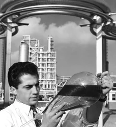 Een laboratoriummedewerker houdt een scheitrechter met olie vast, Dunkirk raffinaderij, Frankrijk, 1950s