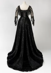 Zwarte avondjurk tot op de grond gedragen door koningin Alexandra, met kralen- en paillettenversiering en met het kenmerkende zwarte zijden naamlint met gouden letters van koningin Alexandra, gemaakt door Barolet of Knightsbridge, Londen, 1908-1910