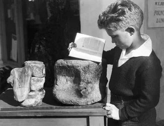 Palos Verdes, Californië: ca. 1927 Een jonge jongen bestudeert archeologie met behulp van een versteende prehistorische wervel gevonden in de nabijgelegen heuvels.