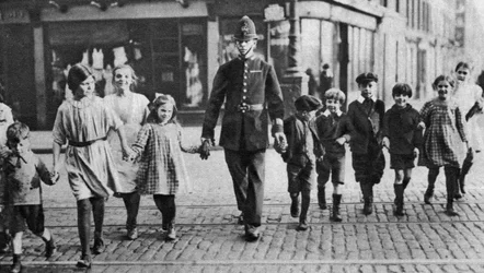Politieagent helpt schoolkinderen de weg oversteken, East End, Londen, 1926-1927