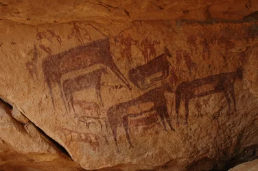Rotstekeningen, Prehistorie: Rotsschildering van een groep vee en een groep figuren waaronder boogschutters in een versierde schuilplaats, in het Uweinat-massief, Soedan (Karkur-Talh). Periode van 8000 tot 3000 jaar v.Chr. Fotografie