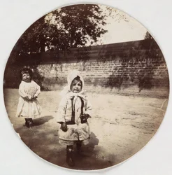 Twee kleine kinderen die langs een muur lopen, ca. 1890