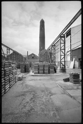 Een algemeen zicht op de Elswick Shot Tower, gesloopt 1968-69, gebruikt voor het maken van loden kogels, met een werf met paletten op de voorgrond, ca. 1955-69