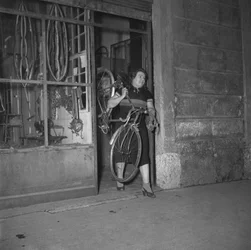 Fietser Alfonsina Strada (Alfonsa Rosa Maria Morini) die haar winkel verlaat op Varesinastraat 80, Milaan, Italië