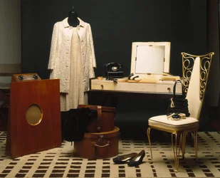 Mode en meubels van de jaren 1920 (Annees folles): Engelse radio Murphy 146, badkamermeubels in ebbenhout makassar en Dominique perkament, witte leren stoel en geslagen ijzer, tafeltelefoon Monophone electric inc Verenigde Staten.