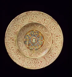 Maiolica bord versierd met een ingewikkeld repetitief knoopontwerp met profielhoofden op de rand en een schild in de centrale plaquette, Italiaans, gemaakt in Toscane