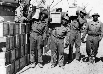 Tweede Wereldoorlog (1939-1945): Midden-Oosten april 1943: In een haven lossen leden van een havenbataljon van het Amerikaanse leger, Afro-Amerikanen, militair materieel.