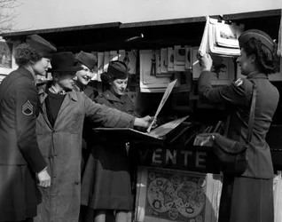 Tweede Wereldoorlog (1939-1945) - Tweede Wereldoorlog (WOII of WO2): Parijs (Frankrijk) maart 1945: Vier Wacs (Women Army Corps) van het Amerikaanse leger praten met een boekspeler aan de oevers van de Seine