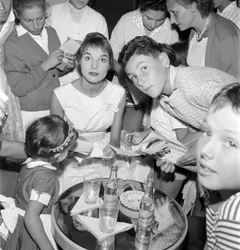 DE ACTRICE EN HET FASHIONMODEL ELSA MARTINELLI OP HET XVIII INTERNATIONALE FILMFESTIVAL OP HET LIDO VAN VENETIË (ze deelt handtekeningen uit aan jonge fans. Op tafel staat een fles Schweppes) - 1957