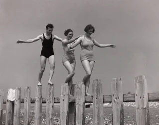Twee vrouwen en een man wandelen langs een golfbreker, ca. 1930s