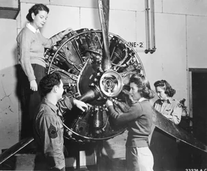 Wespen leren waar de kracht vandaan komt in de B-17 Flying Fortress motor tijdens de B-17 piloottraining op Lockbourne AAB, werkend aan het propellermecanisme, terwijl een crew chief toekijkt, zij zijn (l-r): Patricia Bowser, Ann Waldner en Frances Green