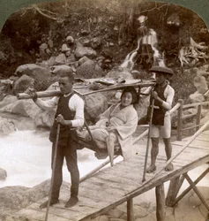 Japanse vrouw in een yamakago bergstoel die de stromende Daiya rivier bij Nikko, Japan, oversteekt