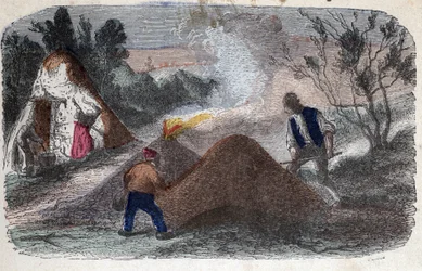 Fabricage van houtskool in de 19e eeuw: kolenmakers voor molenstenen bestaande uit hout en klei, die ze in brand steken. Gravure eind 19e eeuw.