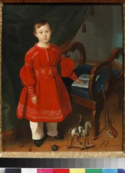 Portret van een jongen in een rode jurk met speelgoed en een alfabetboek