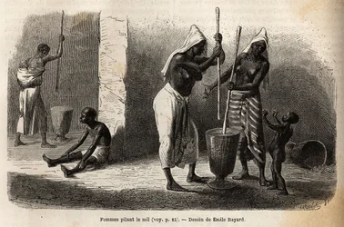 Scène uit het dagelijks leven: vrouwen stampen gierst in Sekou (Niger), omringd door kinderen