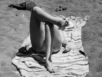 Vrouwelijke benen op een strand, ca 1960 (z/w foto)