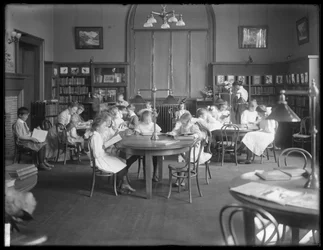 Kinderen lezen in de leeszaal van een niet-geïdentificeerde vestiging van de Queens Borough Public Library, ca. 1910