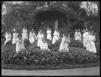 Afstudeerklas van meisjes van het Rooms-Katholieke Weeshuis in de bloementuin, voor de grot van de Maagd Maria, 1912